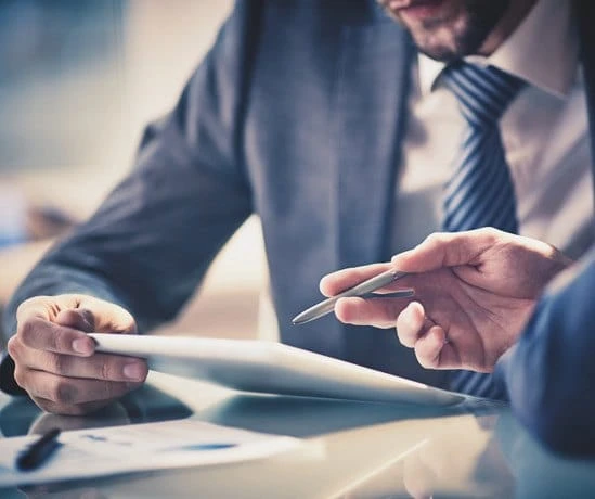 Two business people are sitting at a table with a tablet.